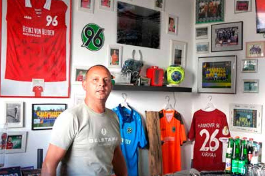 Carsten Braunholz in seinem Büro vor Trikots von Hannover 96